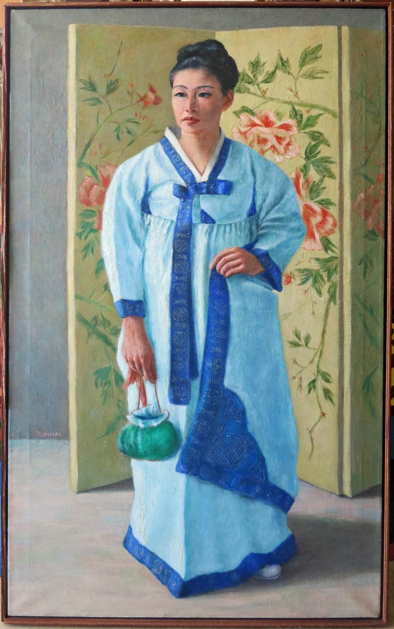A woman in traditional Korean attire holds a green teapot, standing against a backdrop with floral designs. This unique scene embodies the multicultural offerings at Red Coyote Trading Post in Ft. Mohave, AZ, where you'll discover diverse ethnic goods and handcrafted treasures.