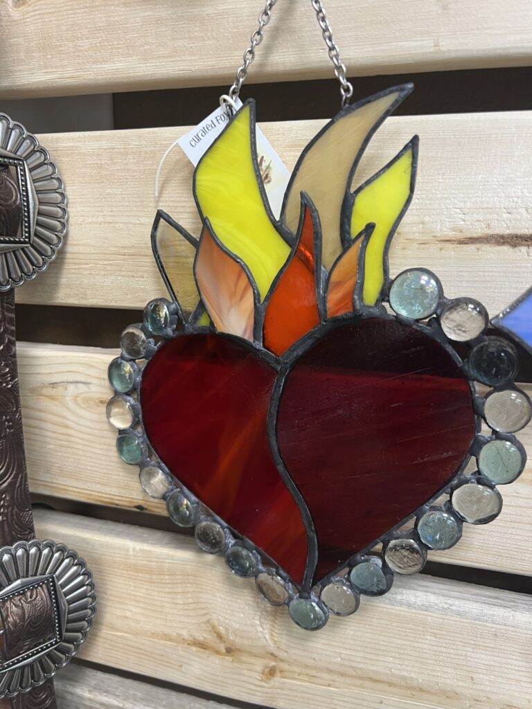 Stained glass artwork of a heart with flames, beautifully crafted for Red Coyote Trading Post in Ft. Mohave, AZ, set against an artisanal wooden background and bordered by intricate circular glass pieces.