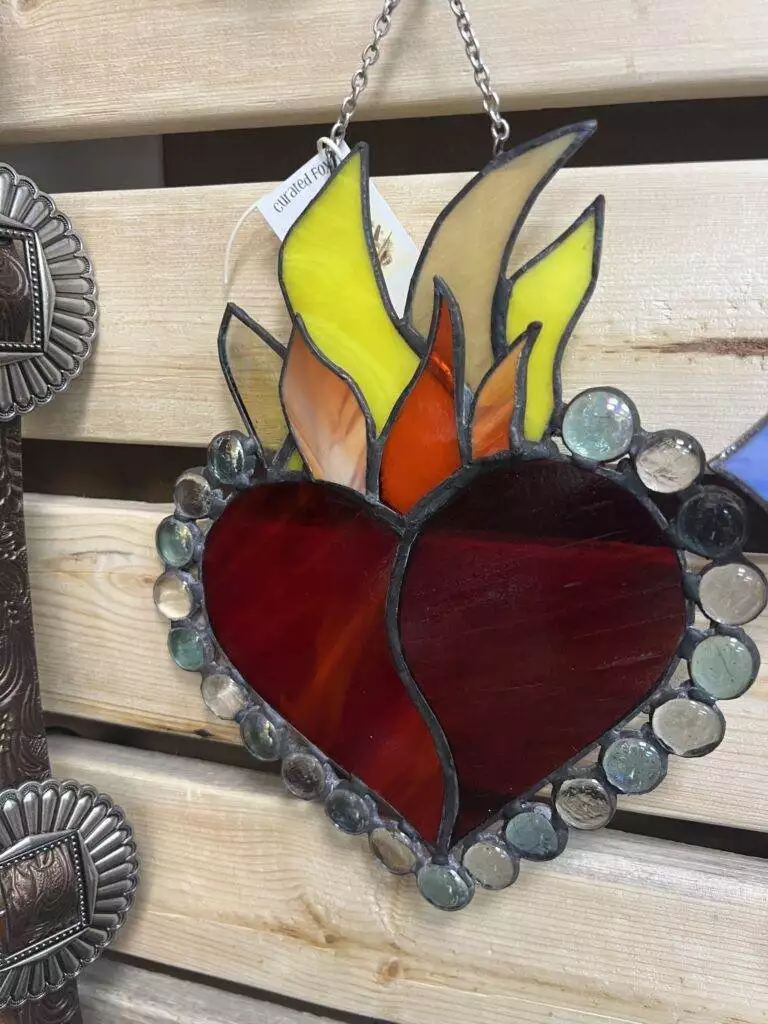 Stained glass artwork of a heart with flames, beautifully crafted for Red Coyote Trading Post in Ft. Mohave, AZ, set against an artisanal wooden background and bordered by intricate circular glass pieces.