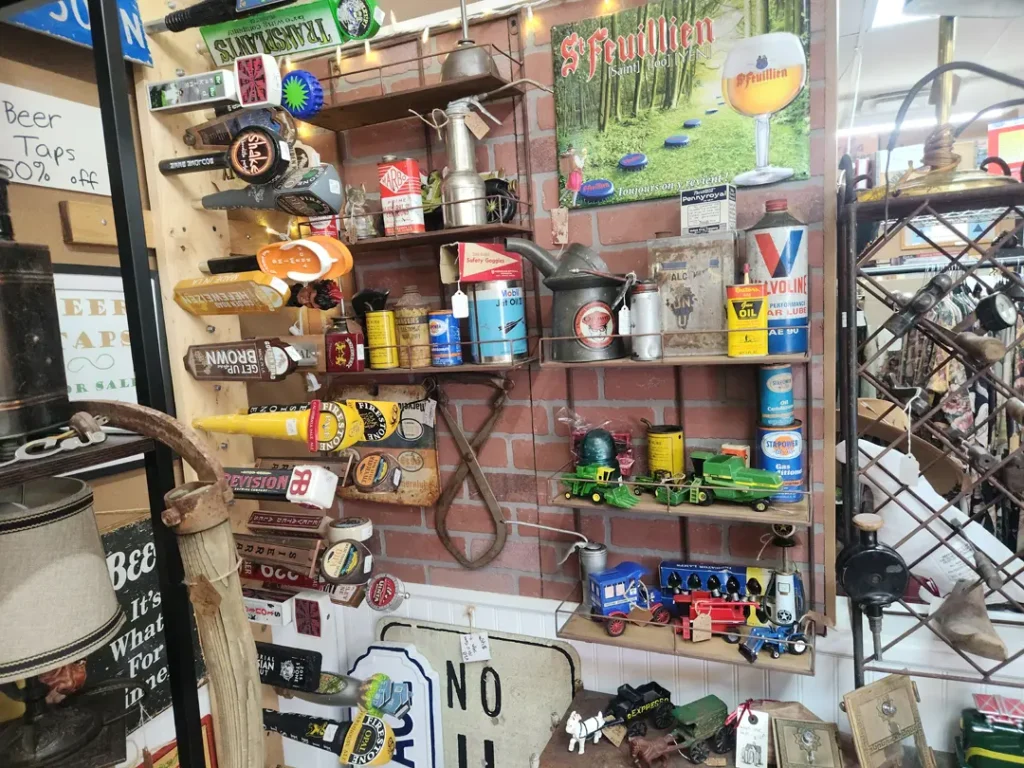 Wall display featuring vintage signs, toys, and assorted memorabilia. Items include toy trains, tin cans, and advertising signs against a brick wall.