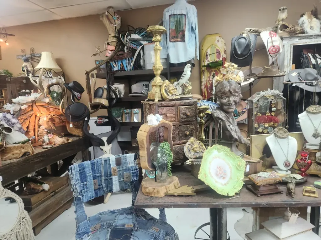 The antique shop displays various vintage items, including jewelry, a bust, candlesticks, and eclectic decor on tables and shelves.