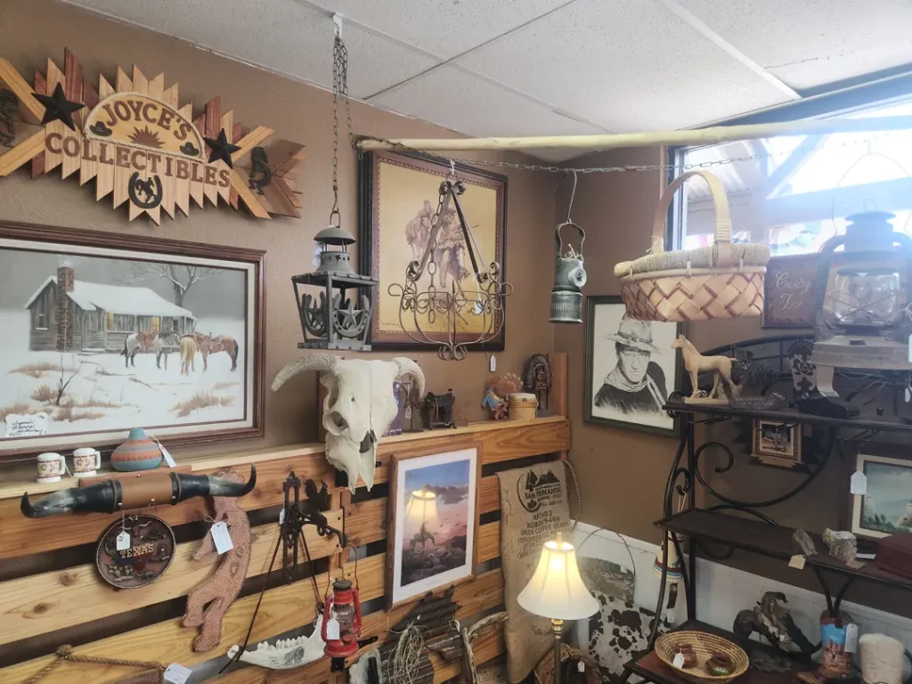 A room filled with vintage Western-themed decor, including paintings, a cow skull, lanterns, and various collectibles. A wooden sign reads 