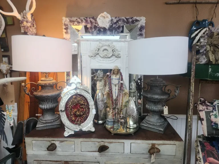 Two ornate lamps on a vintage dresser with decorative mirror