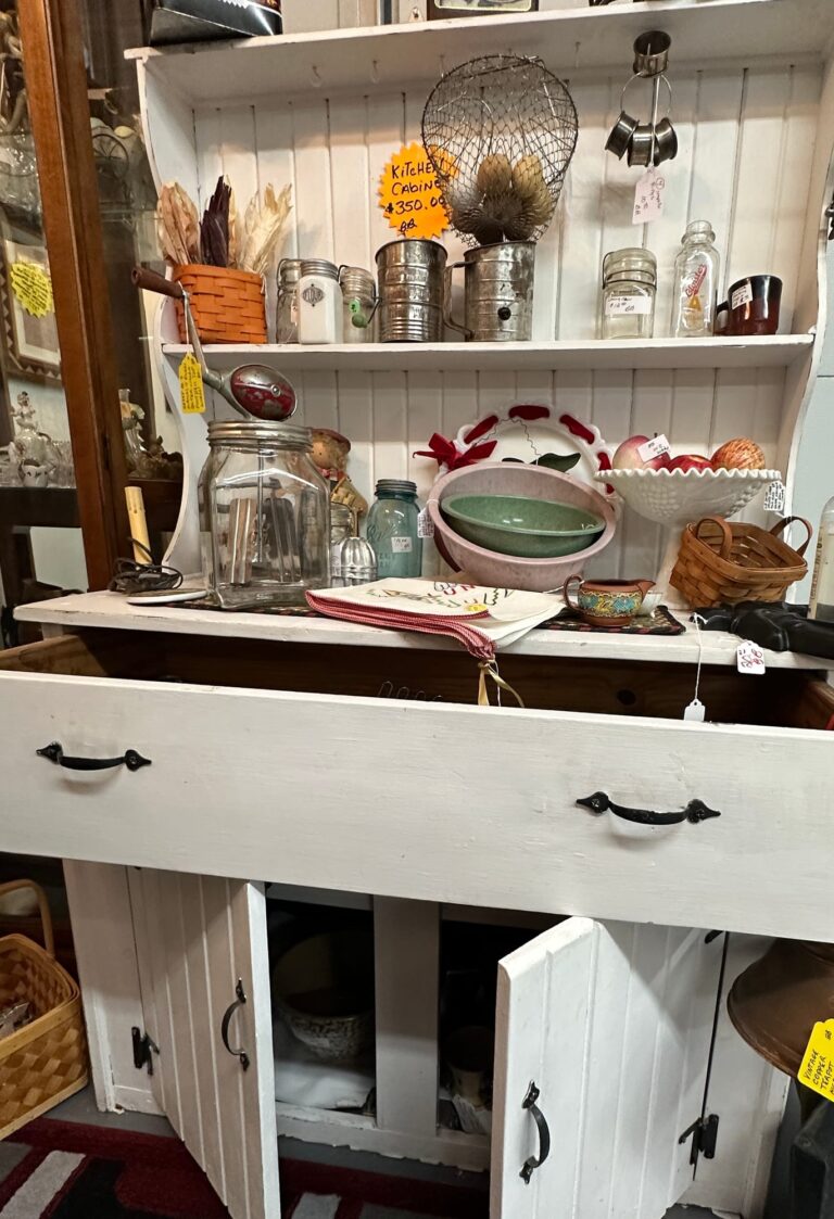 White kitchen hutch filled with vintage kitchenware