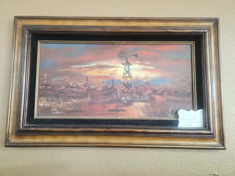Framed painting of rural landscape at sunset with windmill