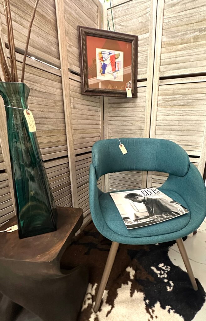 Teal accent chair, green vase, and abstract art in styled corner