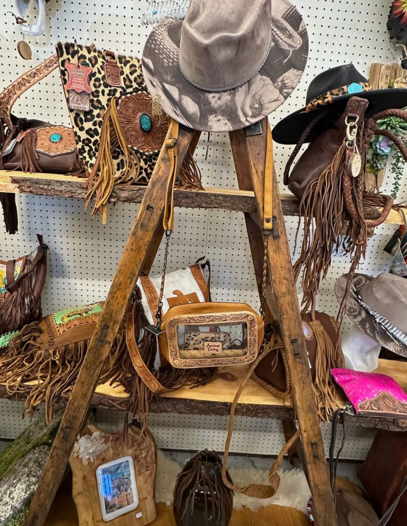 Western hats and fringed leather bags on rustic shelves